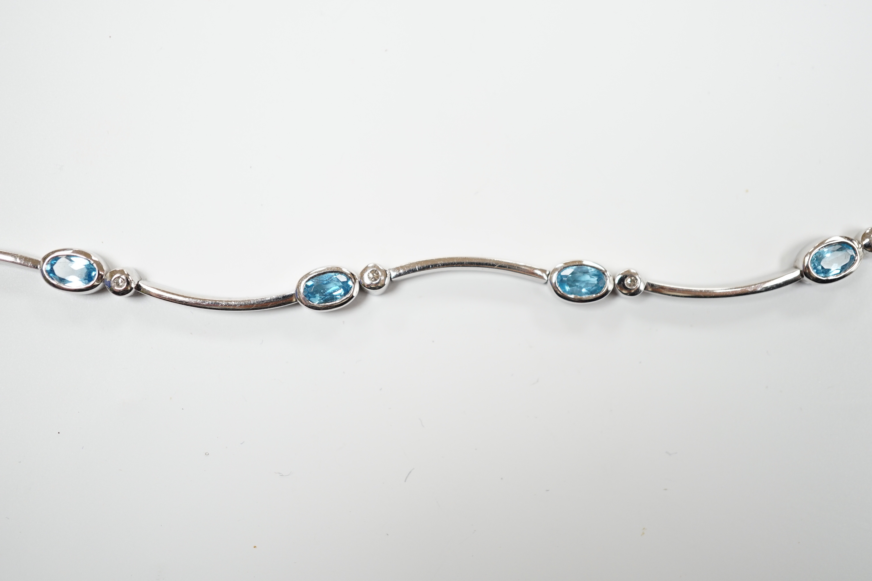 A modern 9ct white gold blue topaz and diamond chip set bracelet, 18.5cm, gross weight 9.1 grams.